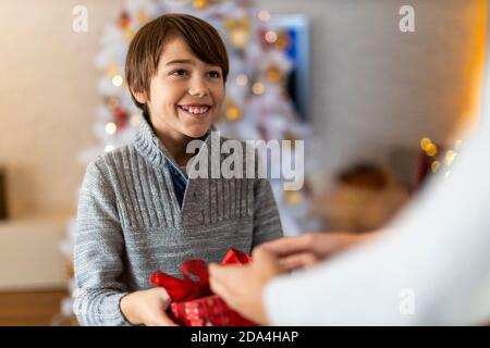 Smiling boy receiving gift from his mother at Christmas Stock Photo