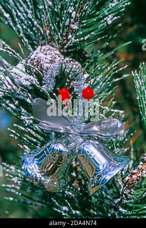 Two silver bells decorating a Christmas tree Stock Photo