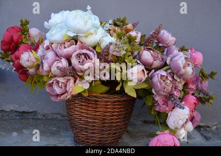 Basket with colorful bouquets of flowers on gray background Stock Photo