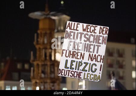 Dresden, Germany. 09th Nov, 2020. Participants stand during a rally of the Islam- and xenophobic Pegida movement on the Altmarkt and hold a poster with the inscription 'All roads of German freedom lead to Leipzig! Deutsche Legida' in front of the Frauenkirche and a Christmas pyramid in the Erzgebirge. Credit: Sebastian Kahnert/dpa-Zentralbild/dpa/Alamy Live News Stock Photo