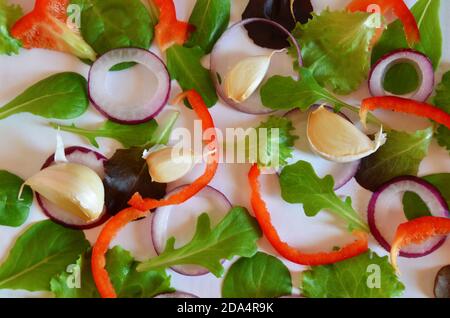 Purple or green basil, Ruccola, purple onion rings, red sweet pepper, garlic on a white background. Frame from fresh greens. Craft background Stock Photo