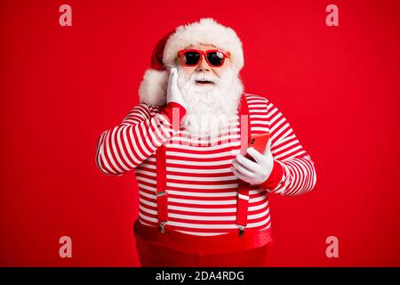 Portrait of his he nice handsome attractive cheerful amazed delighted bearded fat Santa using device app 5g browsing shopping isolated on bright vivid Stock Photo