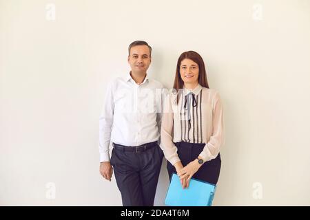 Positive man and woman business partners office workers standing with documents and looking at camera Stock Photo