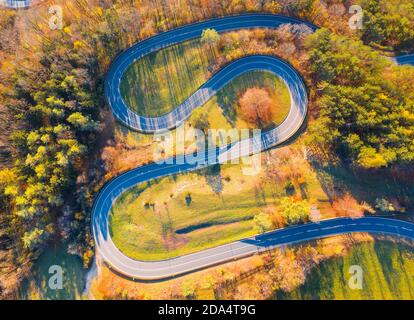 Curvy road up the mountain, aerial view on autumn evening