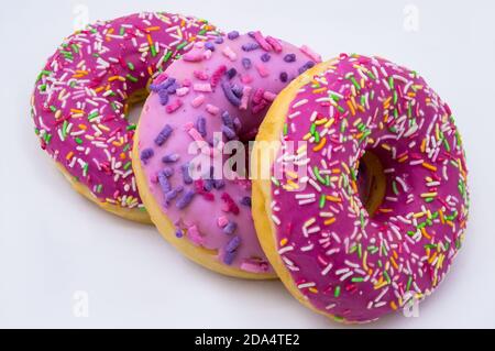 three berry donut, pink donut, three, three donut in a pink glazet, strawberry and raspberry doughnuts, walnut donut on a white background Stock Photo