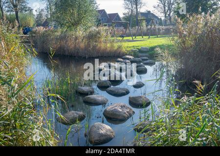 Water playground with large stones in a small stream and wooden play equipment in the background Stock Photo