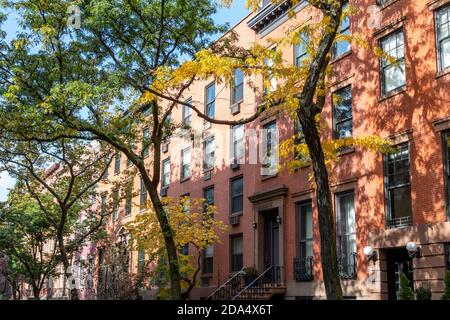 Tree lined street with colorful fall trees and historic buildings in the Chelsea neighborhood of Manhattan in New York City NYC Stock Photo