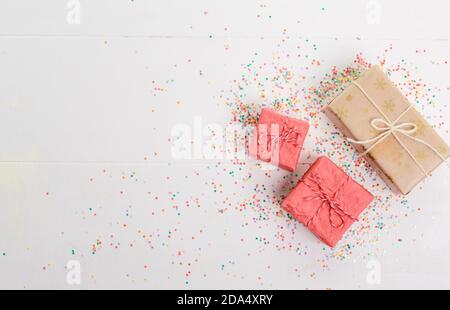 Lots of Christmas gifts in big and small boxes, confetti scattered around on a white isolated background Stock Photo