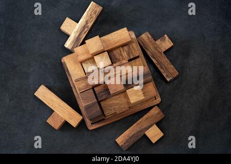 Wooden block brain teaser on dark background. Pieces Close Up. Top view Stock Photo