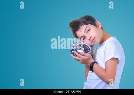School boy with alarm clock in hands isolated on blue. Time to go Stock Photo