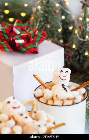 Two snowmen soaking in a hot cup of cocoa surrounded by mini marshmallows. Extreme selective focus with blurred foreground and background. Christmas t Stock Photo