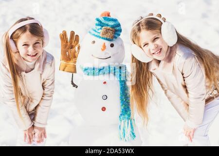 Kids make Snowman on white snow background. Theme Christmas holidays winter new year. Stock Photo