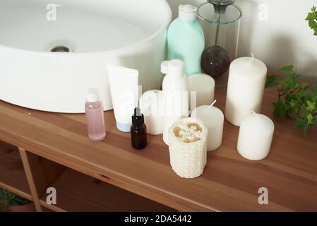 Light-colored bathroom sink with tubes of cream, jars of facial serums and clean towels. The concept of skin care, daily washing and cleanliness. Stock Photo