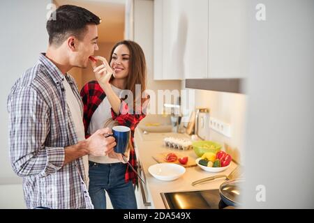 Man eating the sliced vegetable from his wife hand Stock Photo