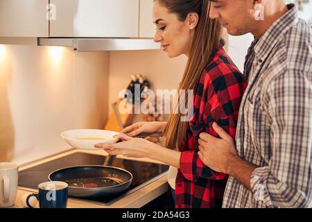 Hungry husband watching her wife making an omelet Stock Photo