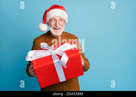 Portrait of his he nice attractive cheerful cheery kind elderly bearded grey-haired Santa father holding in hands christmastine big large giftbox sale