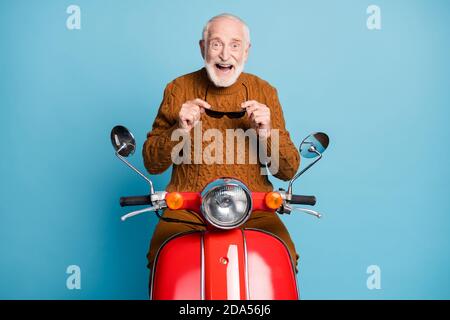 Portrait of his he nice attractive funky cheerful cheery glad delighted bearded grey-haired man riding moped having fun tourism exploring city Stock Photo