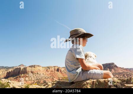 young boy sitting on rock with his dog Stock Photo