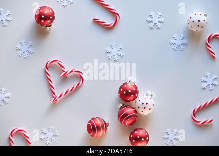 Heart shapes made from candy canes, red white spotted trinkets on white textile. Hand hold heart. Stock Photo