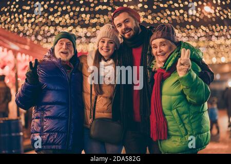 Portrait of nice attractive cheerful family embracing having fun spending time visiting street city urban market newyear tradition wintertime showing Stock Photo