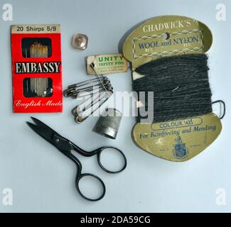 Flat lay studio shot of vintage scissors, needles, a thimble, safety pins and wool wound on a card - sewing, mending and repair items Stock Photo