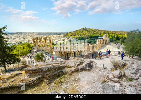 Tourists admire the Odeon of Herodes Atticus, or Greek Theatre, on the Acropolis of Athens Greece with Philopappos Hill in the background Stock Photo