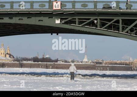 Silhouette of skier riding on ice of the frozen Neva River under the Palace Bridge in winter at sunset Stock Photo