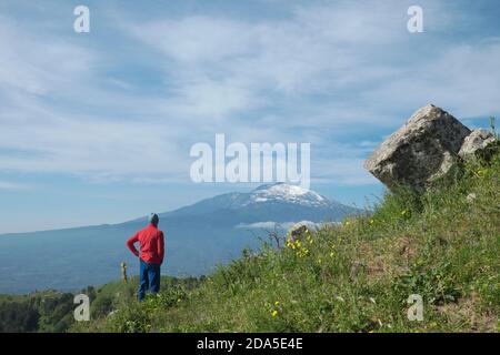 man looking at Etna Mount and cirrus clouds against blue sky, Sicily