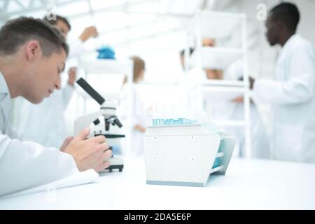 male research scientist looks at biological samples under microscope. Stock Photo