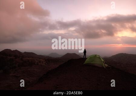 man looking the sunrise from a wilderness area of old volcanoes in Etna National Park, Sicily Stock Photo