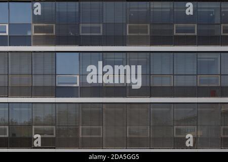 Background of exterior facade of modern building with detail horizontal outer louver and reflected glass windows on rectangular frame pattern. Stock Photo