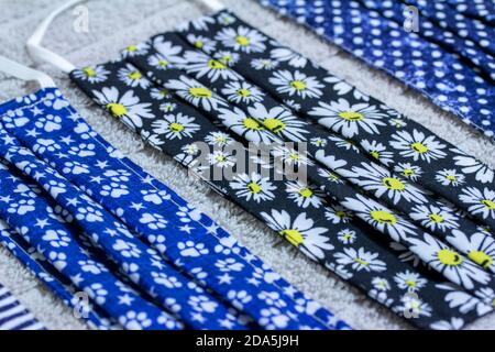Close up view of four various print hand-washed COVID protective face masks, drying on a cotton towel on kitchen table Stock Photo