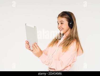 Cute smiling teen girl with headphones and tablet in her hands isolated on white background Stock Photo