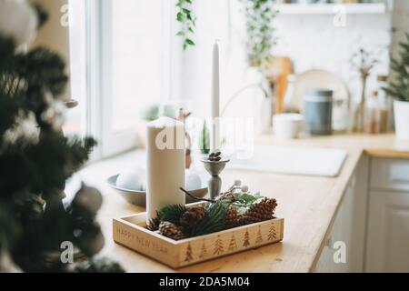 Christmas composition of white candles, pine branches and cones on the kitchen corner at home Stock Photo