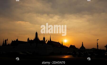 Sunset skyline of one of Bangkok's famous landmarks 'The Grand Palace' with it’s dazzling golden temples in silhouette set against the setting sun. Stock Photo