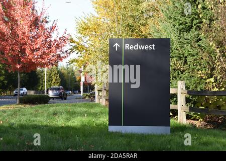 Big black sign on grass next to the street showing direction to Microsoft Redwest campus in Redmond, Washington, USA. Taken in Autumn. Stock Photo