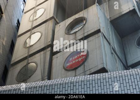 Close-up of the iconic Kisho Kurokawa-designed Nakagin Capsule Tower in Tokyo. A sign in a window reads '#Save Nagakin'. (October 2020) Stock Photo