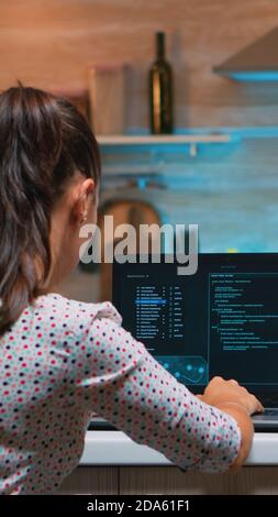 Woman remote thief stealing data from company hacking system from home. Programmer writing a dangerous malware for cyber attacks using performance laptop during midnight. Stock Photo