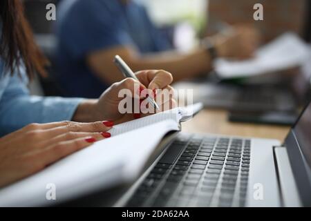 Female hands hold pen and diary next to laptop at work table. Stock Photo