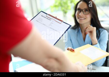 Courier delivers parcel mail to a businesswoman at her desk