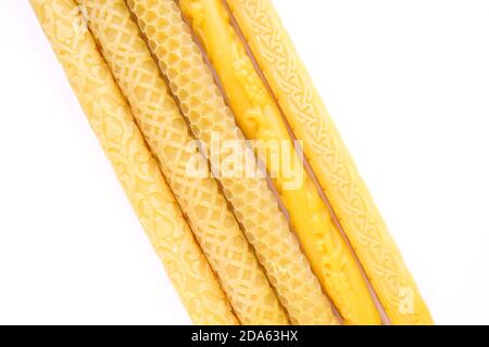 Large yellow wax candles with different cut out pattern on isolated white. Stock Photo