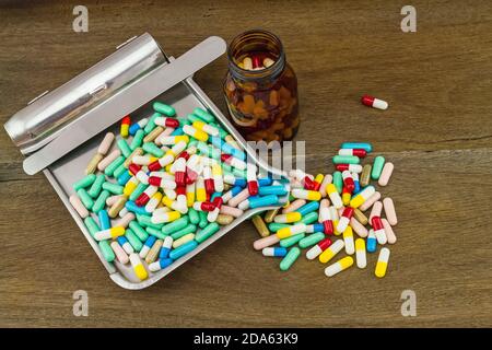 Colorful tablets medicine in the drug counting tray and black bottle on wooden background Stock Photo