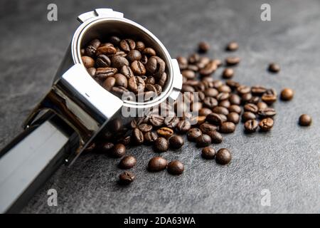 Roasted coffee beans in coffee filter holder on black table. Stock Photo