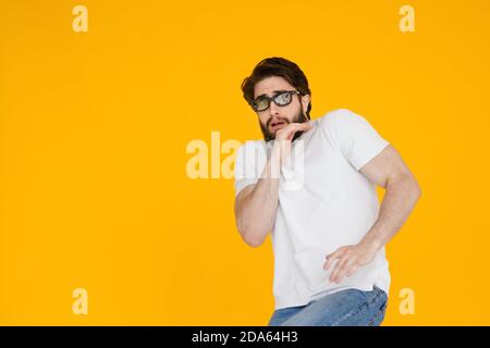 Portrait of a shaggy, bearded scared man in 3D glasses with an open mouth and big eyes, on a yellow background. Stock Photo