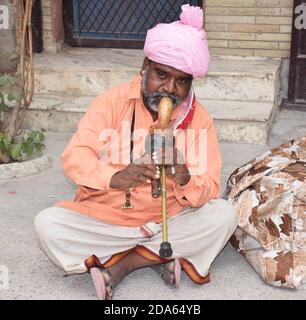 Indian Snake charmer performing with his musical instrument also called as Pungi or Been in Hindi Language. Close up shot Stock Photo