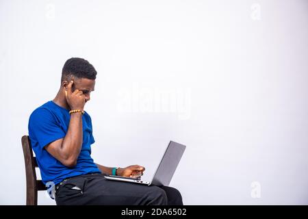 young black man looking thoughtful and having issues with using his credit card and laptop Stock Photo