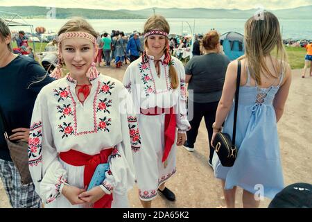 Girls in folk Ukrainian costumes walk along a shopping street at the Karatag music festival. Krasnoyarsk region. Russia. Stock Photo