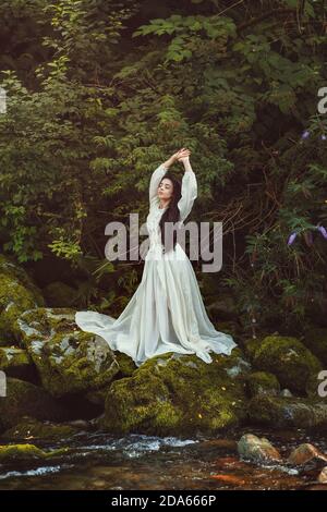 Beautiful romantic woman posing among green leaves Stock Photo