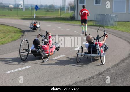 Disabled Athletes training with their Handbike with Runner Close to Them. Stock Photo