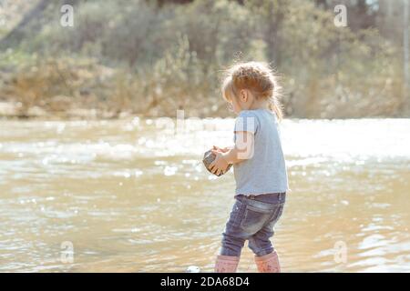 little girl playing with rocks by the river Stock Photo